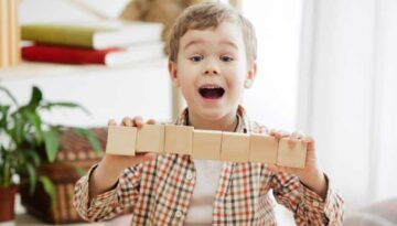 little-child-sitting-floor-pretty-smiling-surprised-boy-playing-with-wooden-cubes-home_155003-40155