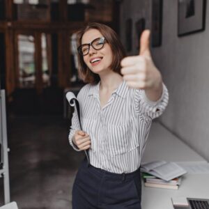 shot-charming-business-woman-glasses-showing-thumbs-up-posing-with-huge-amount-papers-office_197531-13419